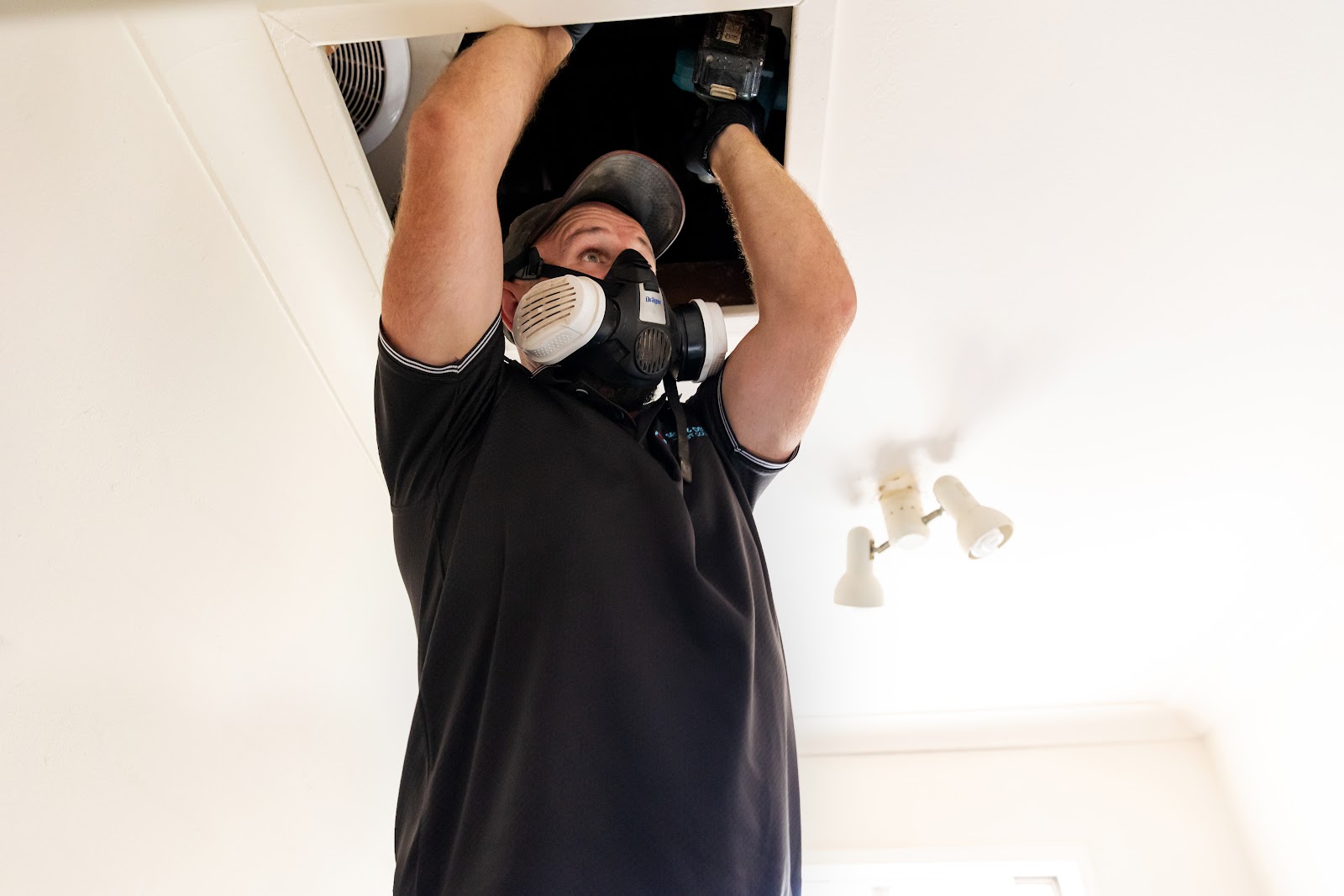 A technician enters a ceiling manhole for an inspection